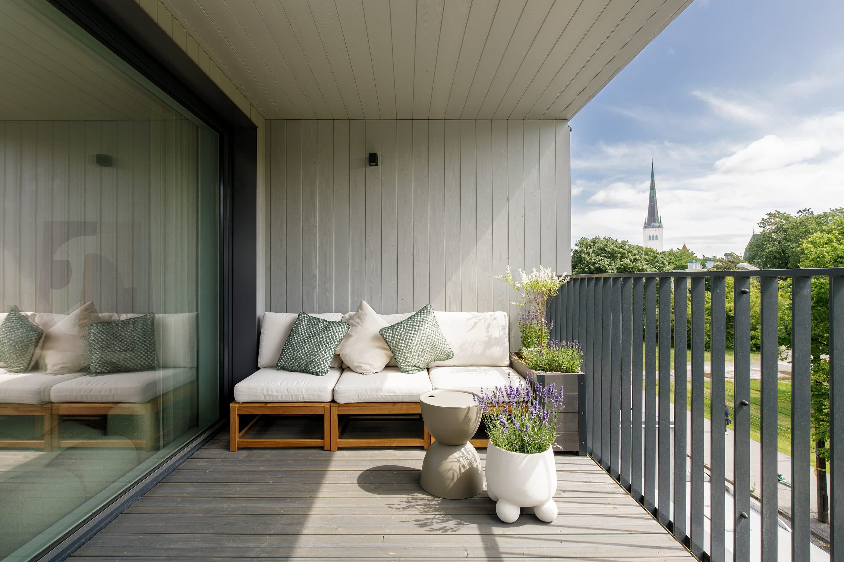 Terrace bench with cushions and lavender planters, an Old Town spire rising beyond the trees